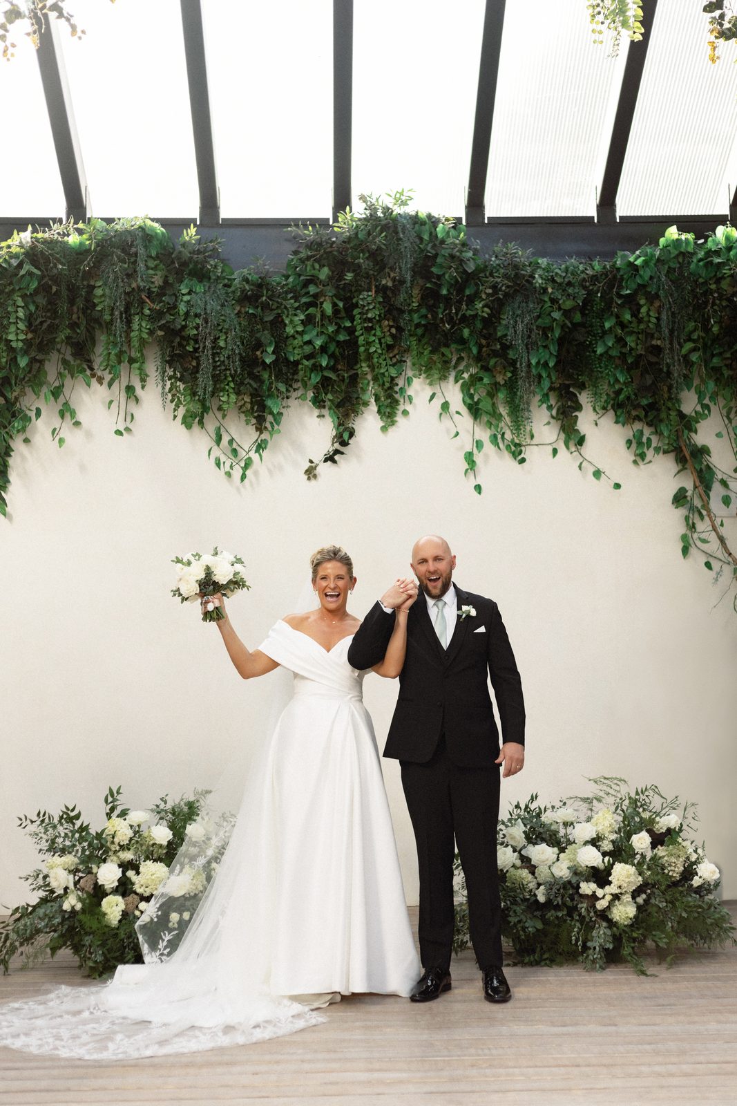 Katie and Mark at Greenhouse Two Rivers — the couple walking together under the glass roof
