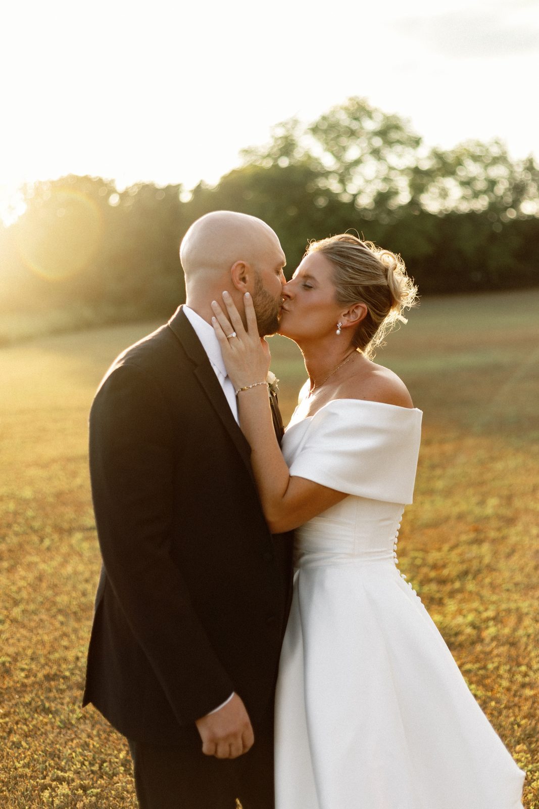 Golden-hour couple portrait in the open field beside Greenhouse Two Rivers